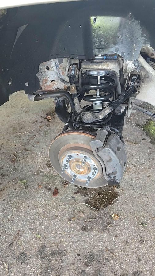 Front brake rotor, hub and caliper exposed with the wheel removed