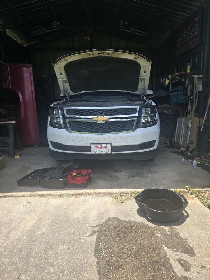 Oil and filter change underway on a Chevrolet Tahoe with a drain pan in place